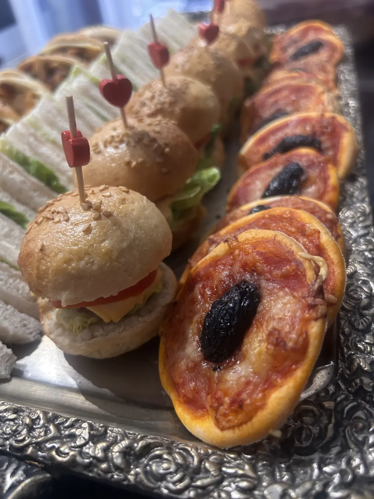 Mini-burgers piqués d'un cœur et mini-pizzas maison sur un plateau argenté