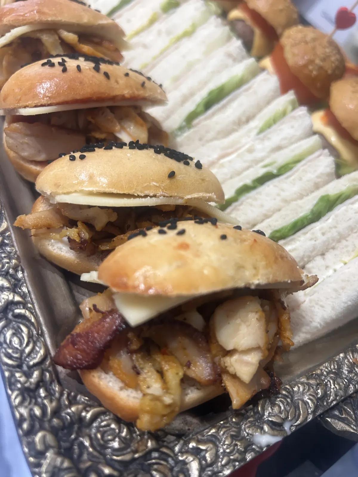 Mini-burgers au sésame noir et mini-sandwichs sur un plateau argenté